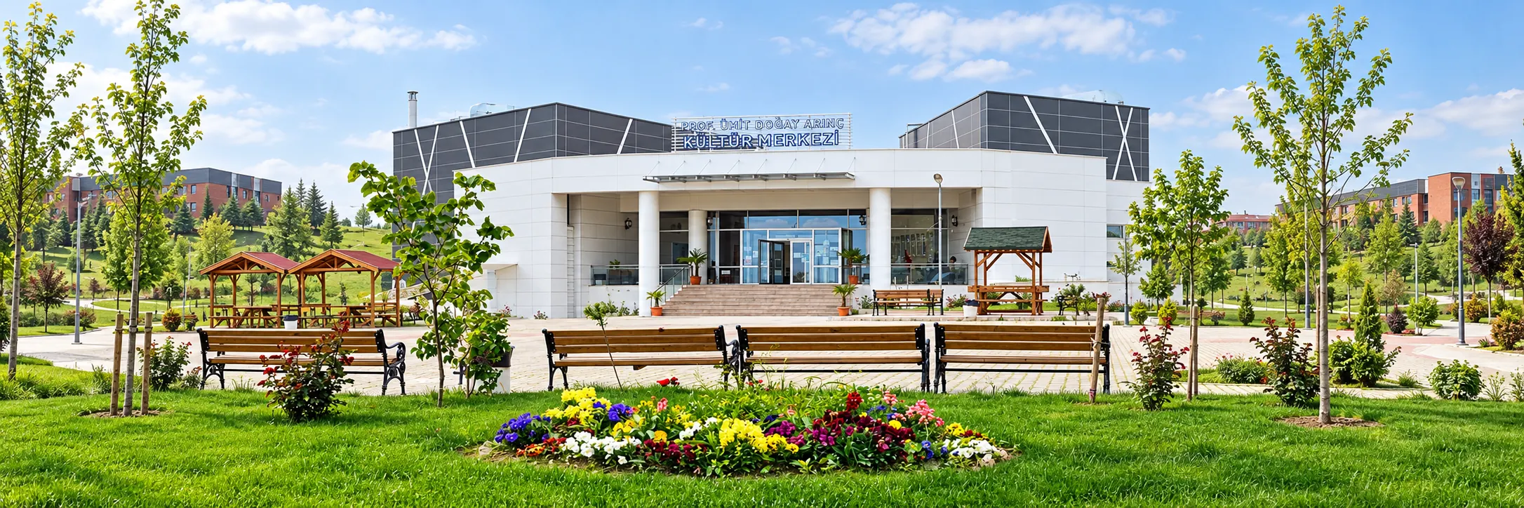 Prof. Ümit Doğay Arınç Kültür Merkezi'nin girişi, önünde çiçekli bahçe ve banklar