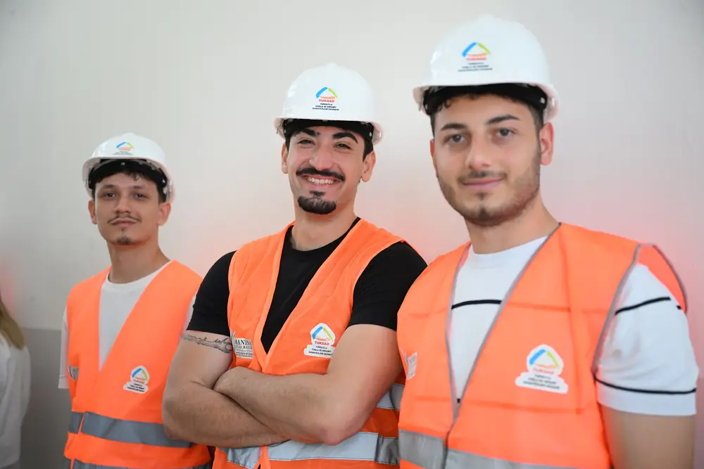 Baret ve ikaz yeleği giymiş üç MCBÜ mühendislik öğrencisi