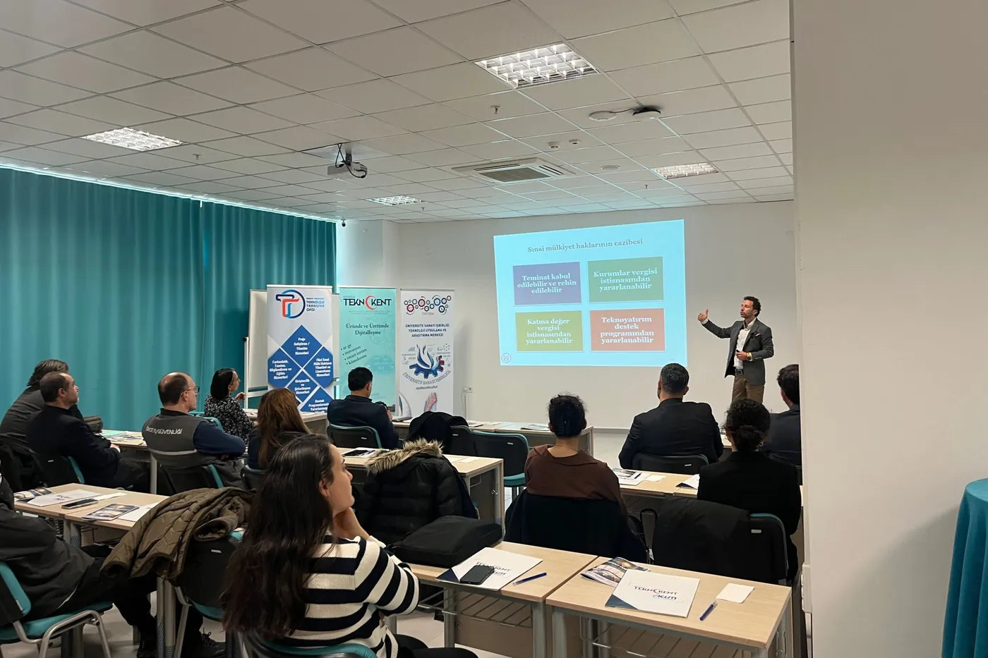 Manisa Teknokent'te patent ticarileştirme konferansında sunum yapan konuşmacı ve dinleyiciler